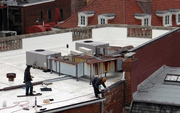 Painters working on a Washington, D.C., roof to make it a light-reflecting white.